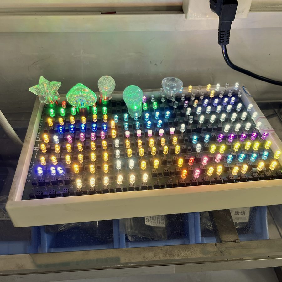 LEDをボードに挿して点灯させ発色を確認している検査の写真